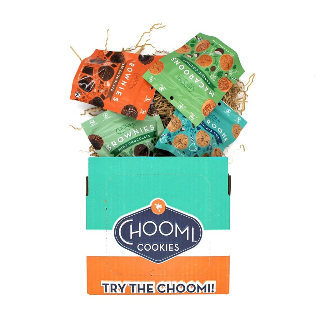 Colorful Choomi Naturals box with four bags of macaroons and brownies coming out the top. 