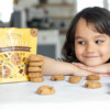 Child looking at Choomi Crunchy Chocolate Chip bag with a smile